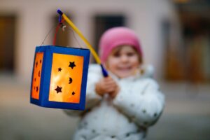 child holding up paper lantern for the lantern parade