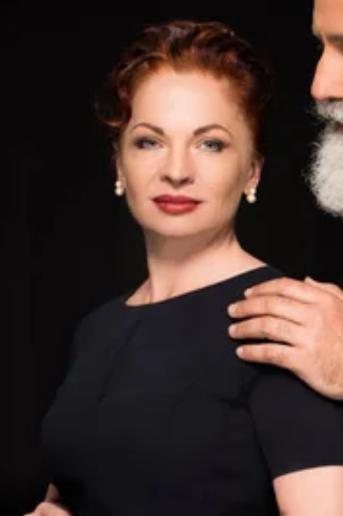 Inspiration picture for Constanza Brisbane, red haired woman in a black dress.